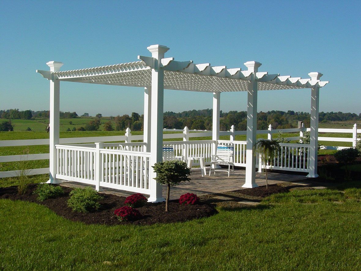 A white pergola is in the middle of a grassy field.