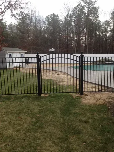 A white fence with a gray border is surrounded by tall grass