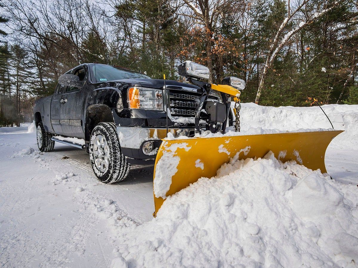 A truck is plowing snow on a snowy road.