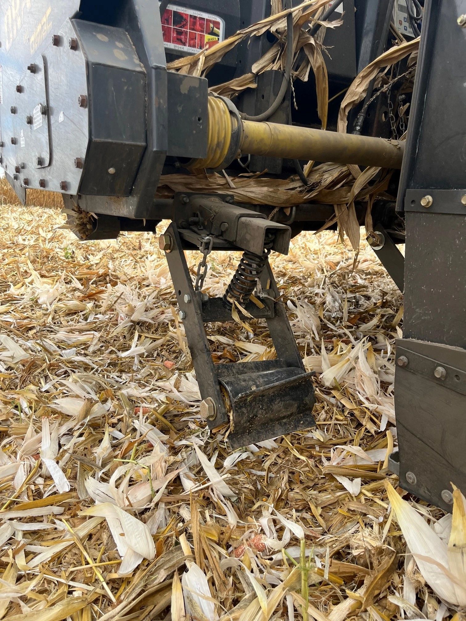A close up of a tractor in a field of corn stalks.