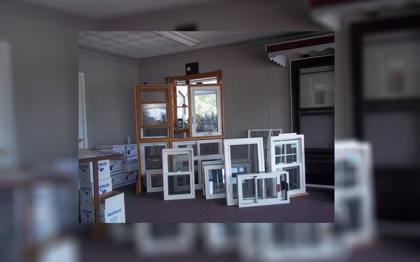 Windows display in a showroom. Various styles in wood and white frames are on the floor.