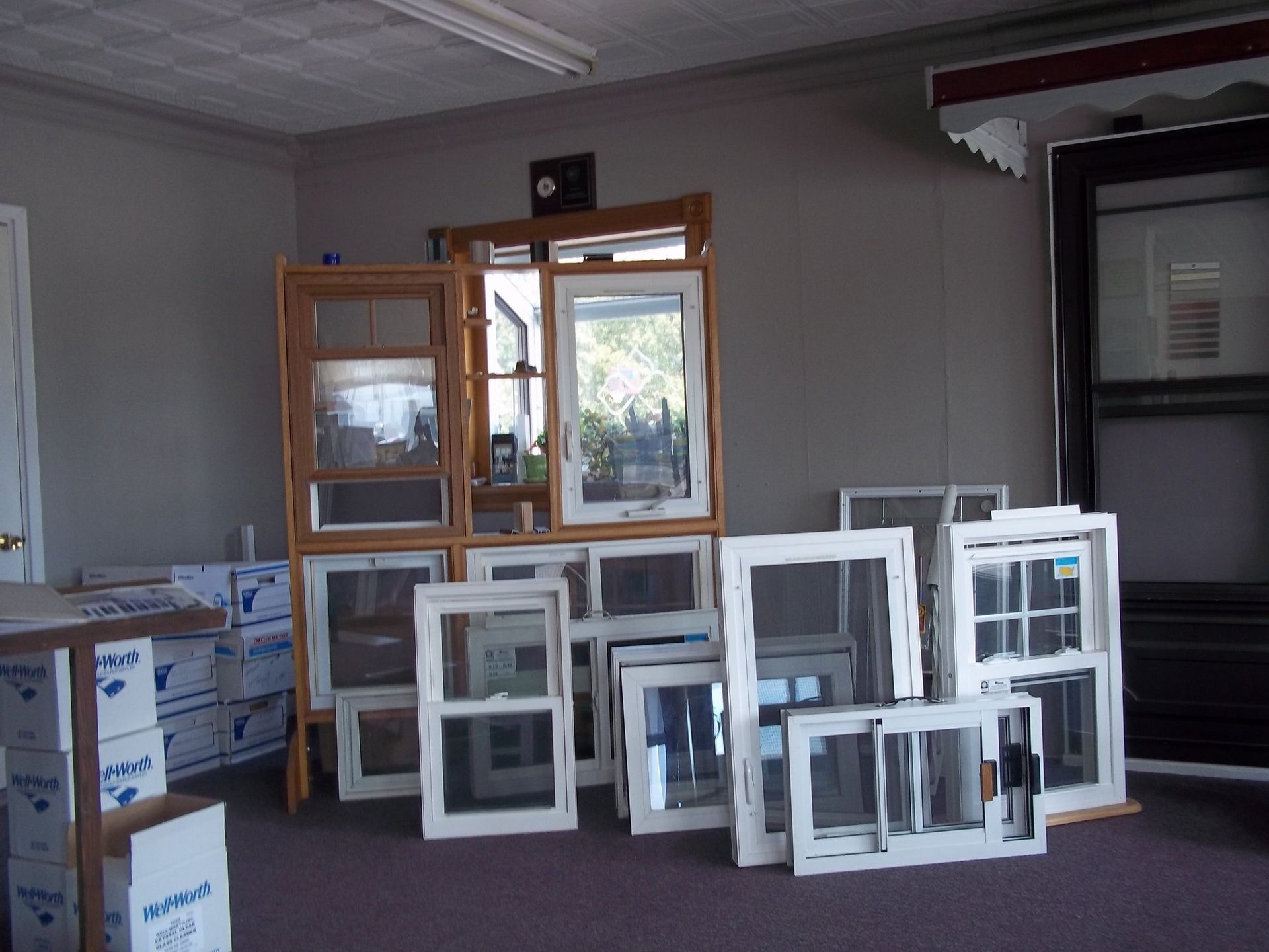 Windows on display in a showroom; various sizes and styles, brown wood and white frames.