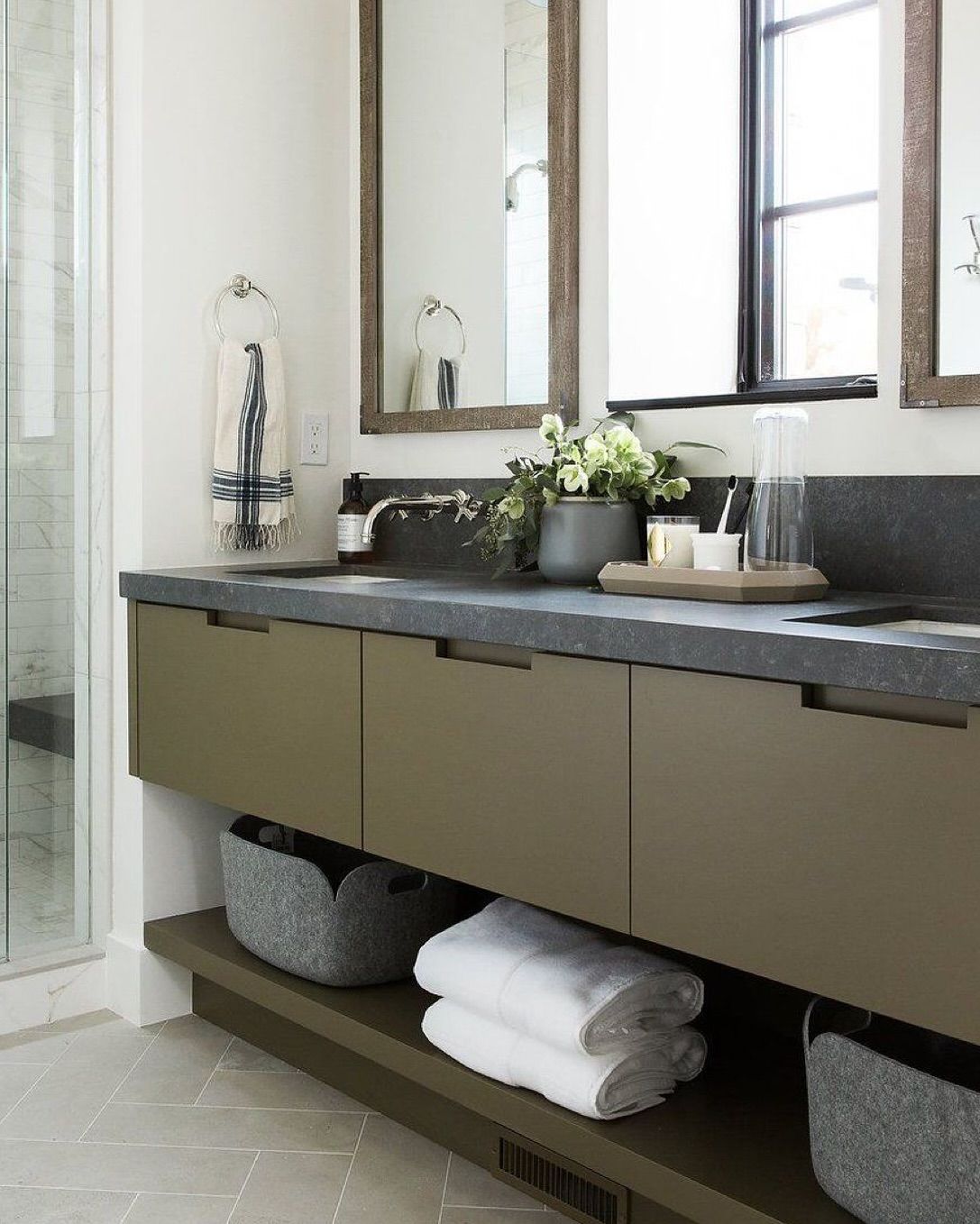 Modern bathroom with olive green vanity, dark countertop, and decorative elements.