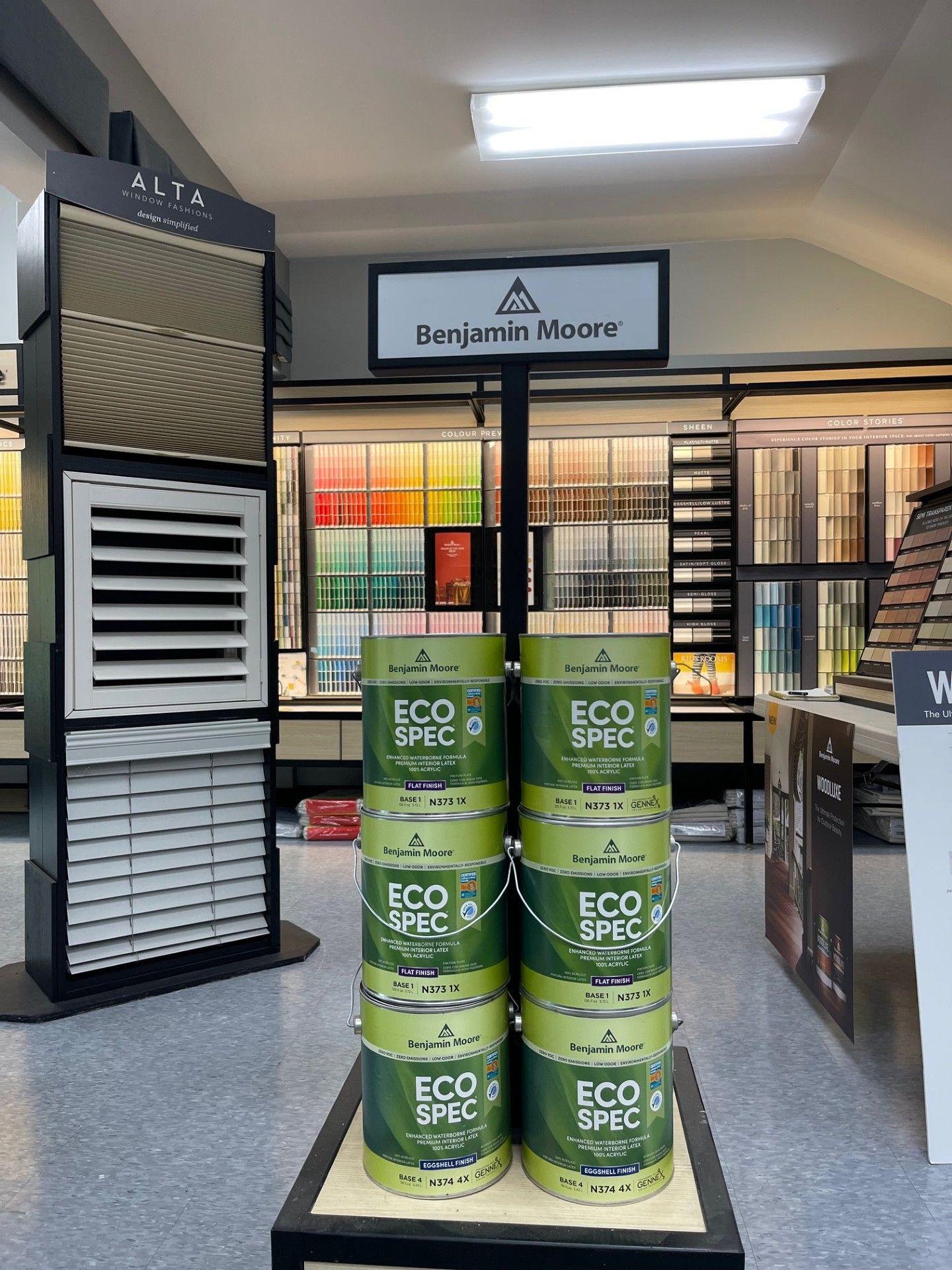 Benjamin Moore paint display in a store, with paint cans stacked and color swatches visible in the background.