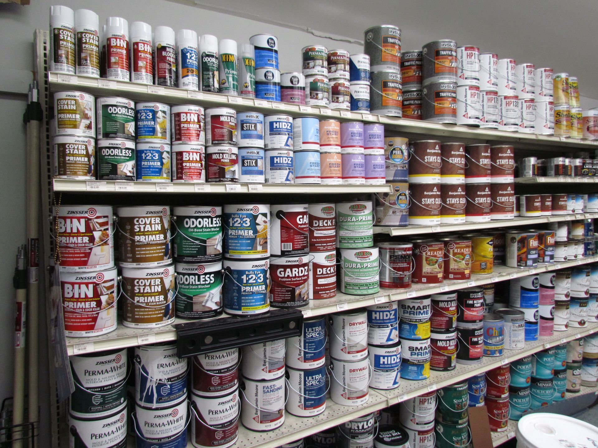 Shelves stocked with paint cans and spray paint in a store.
