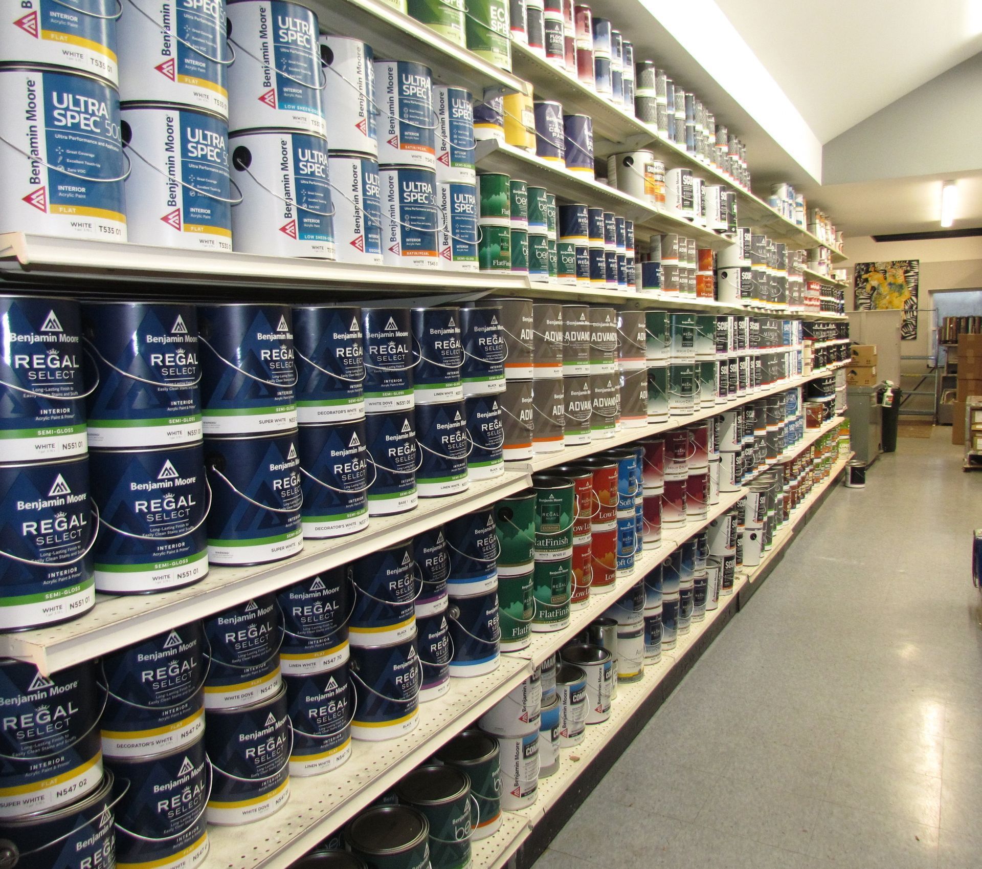 Rows of paint cans in various colors on shelves in a store aisle.