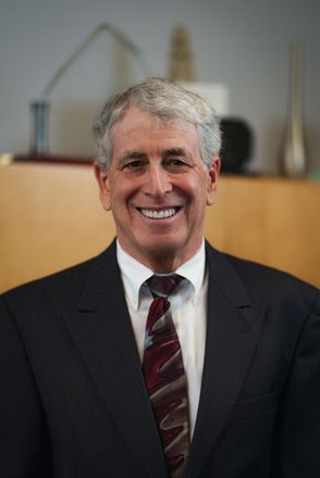 A man in a suit and tie is sitting at a conference table.
