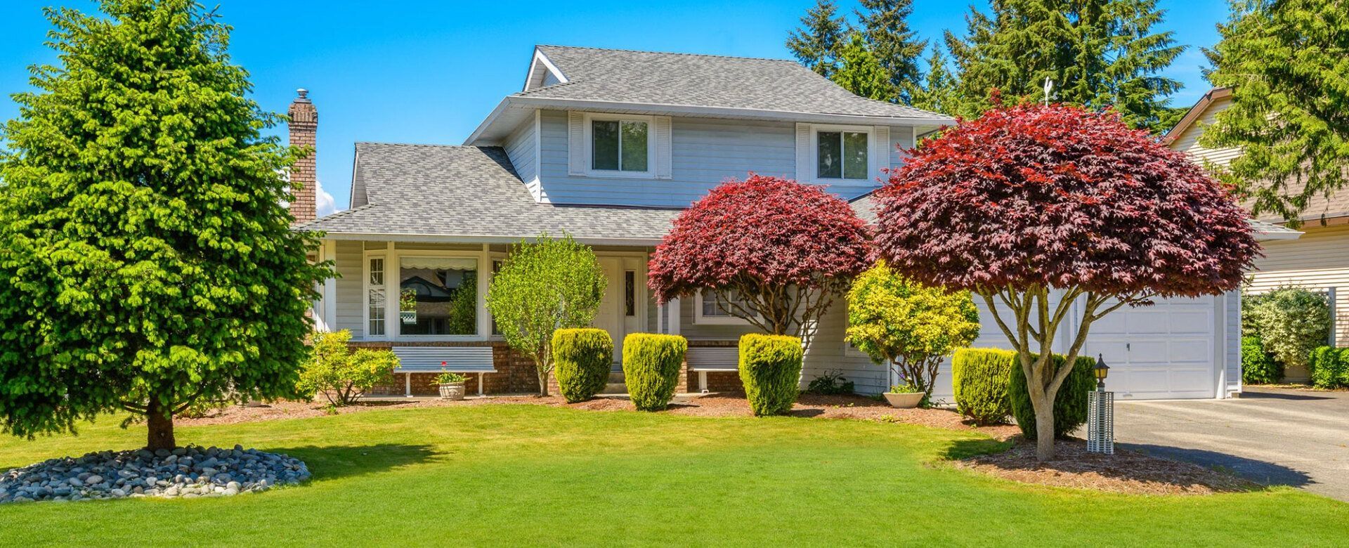 A large white house with a lush green lawn and trees in front of it.