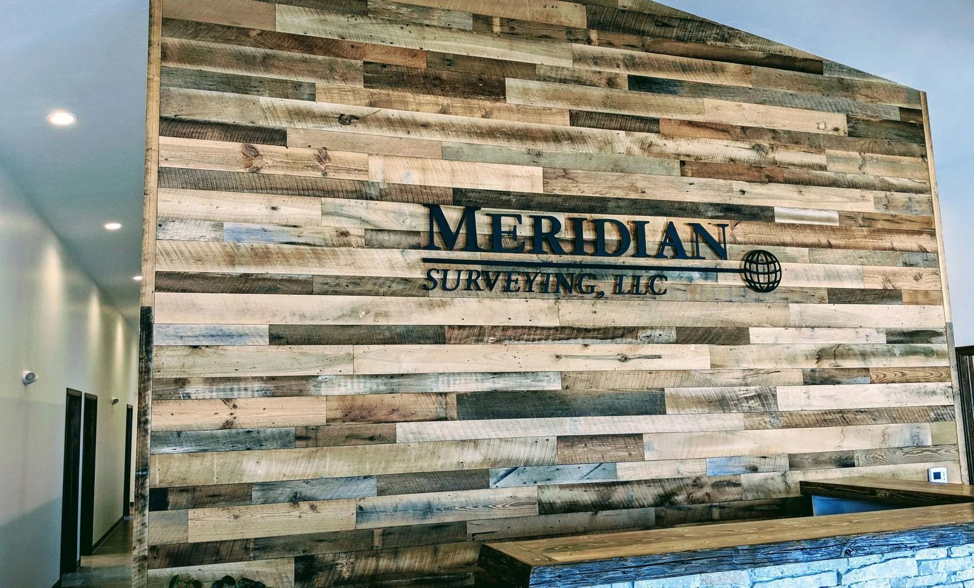 A reception area wall with a rustic reclaimed wood finish features a metal sign reading 