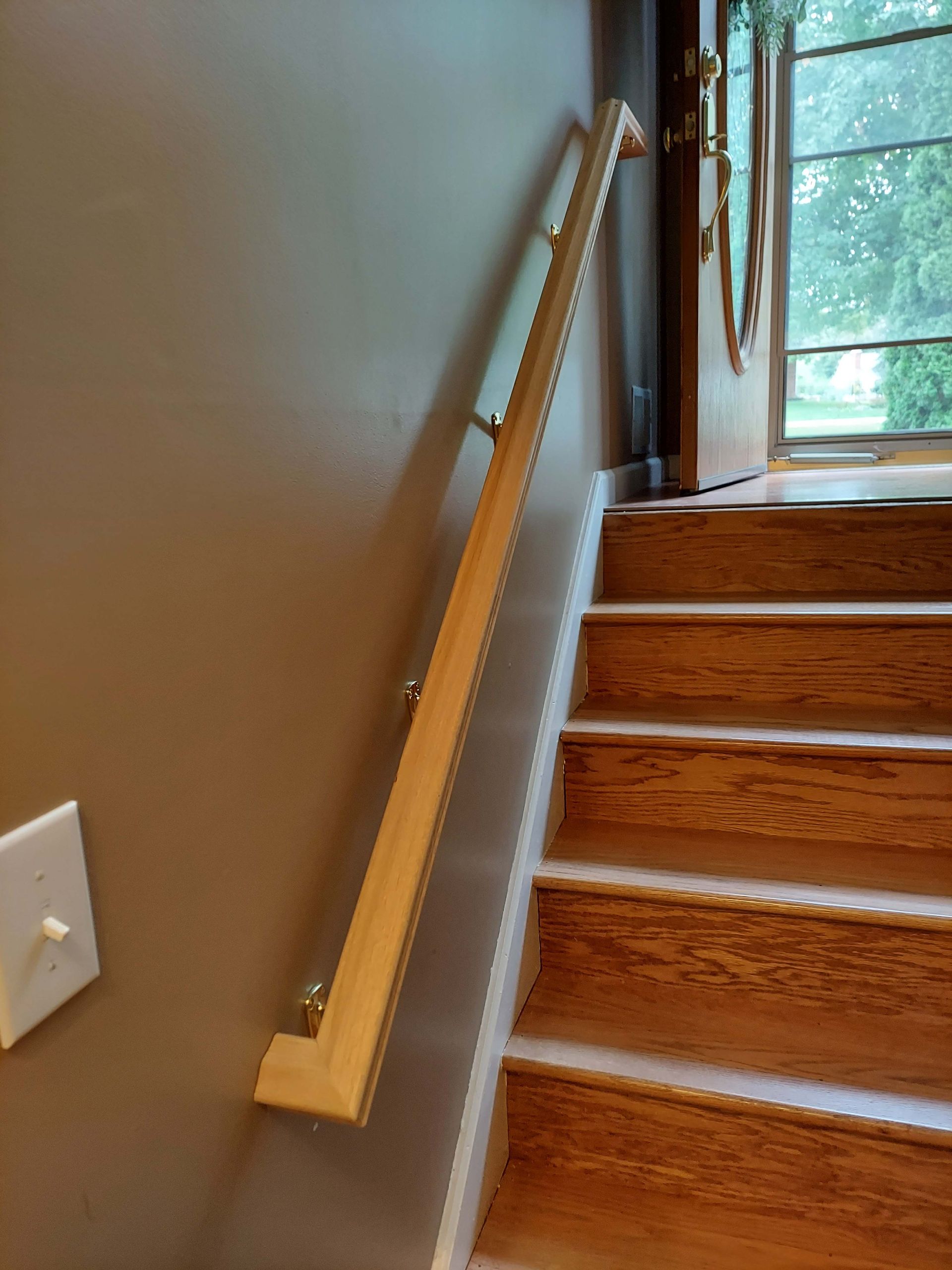 A wooden staircase with a glass railing and a door in the background