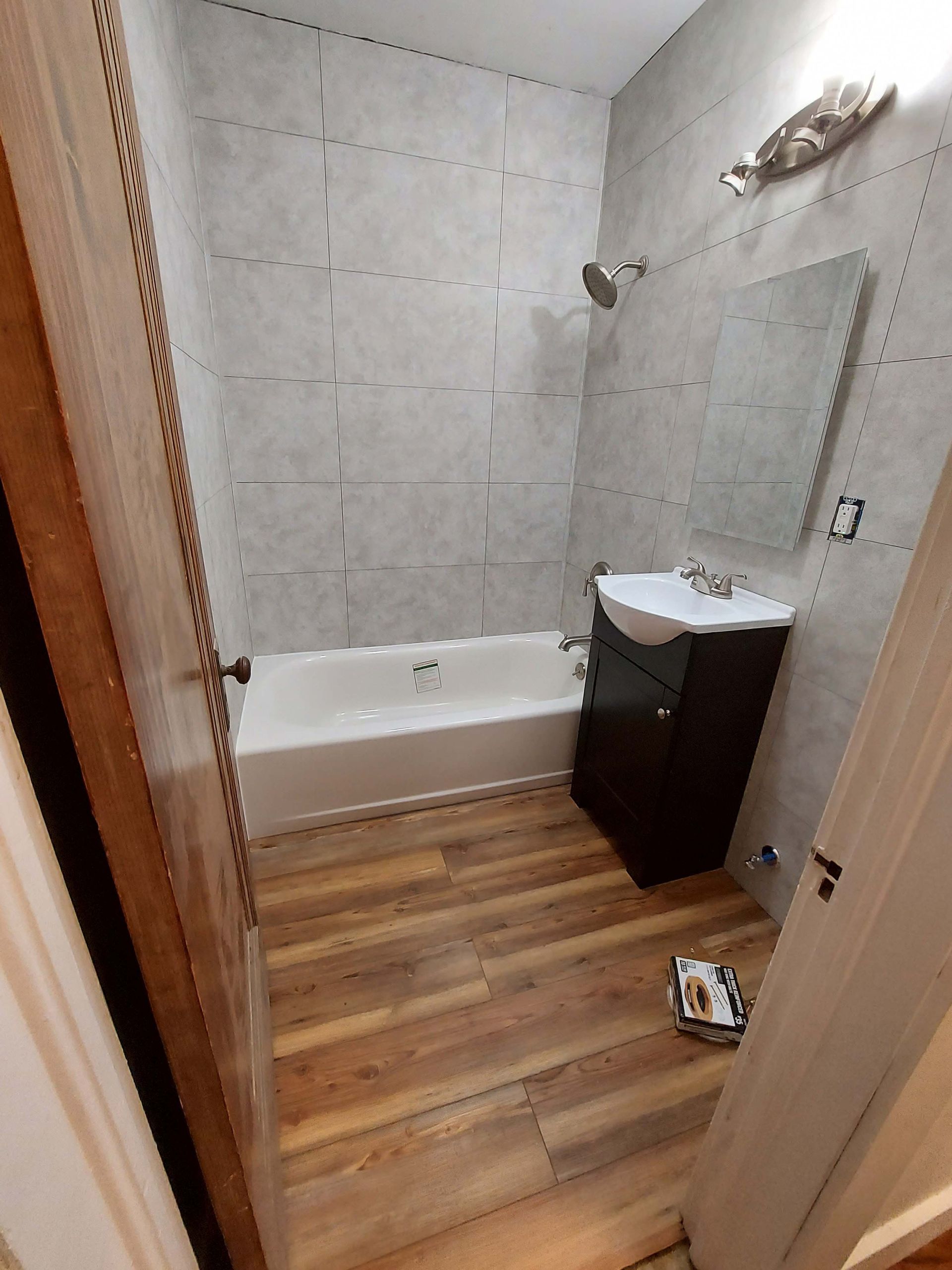 A bathroom with a bathtub , sink and mirror.