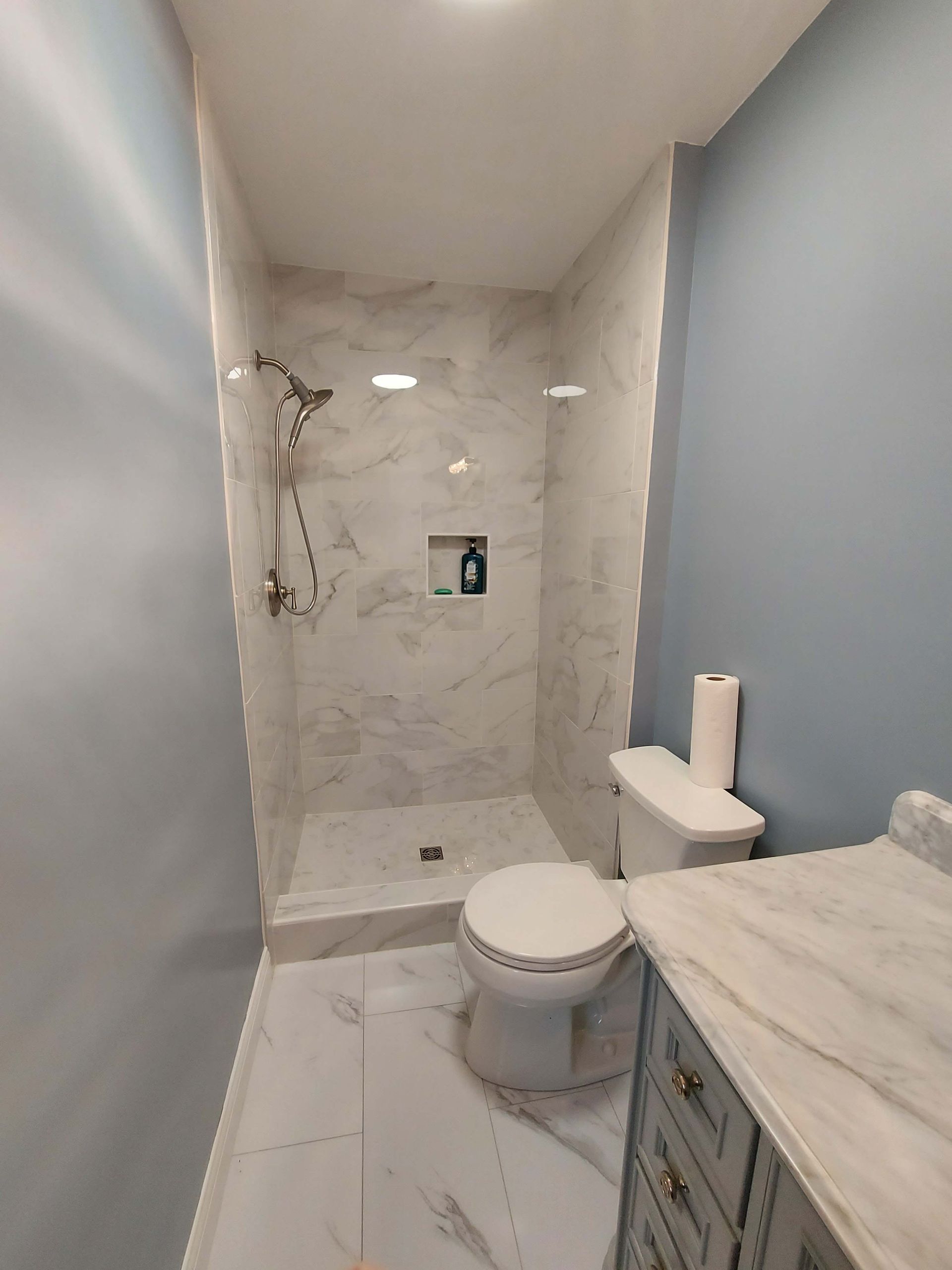 A bathroom with a toilet , sink and shower.