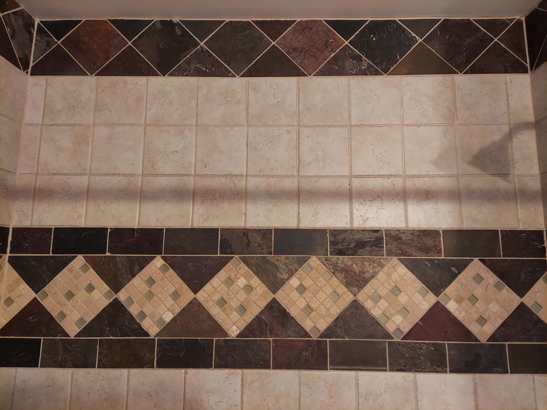 A tiled shower floor with a brown and white tile border