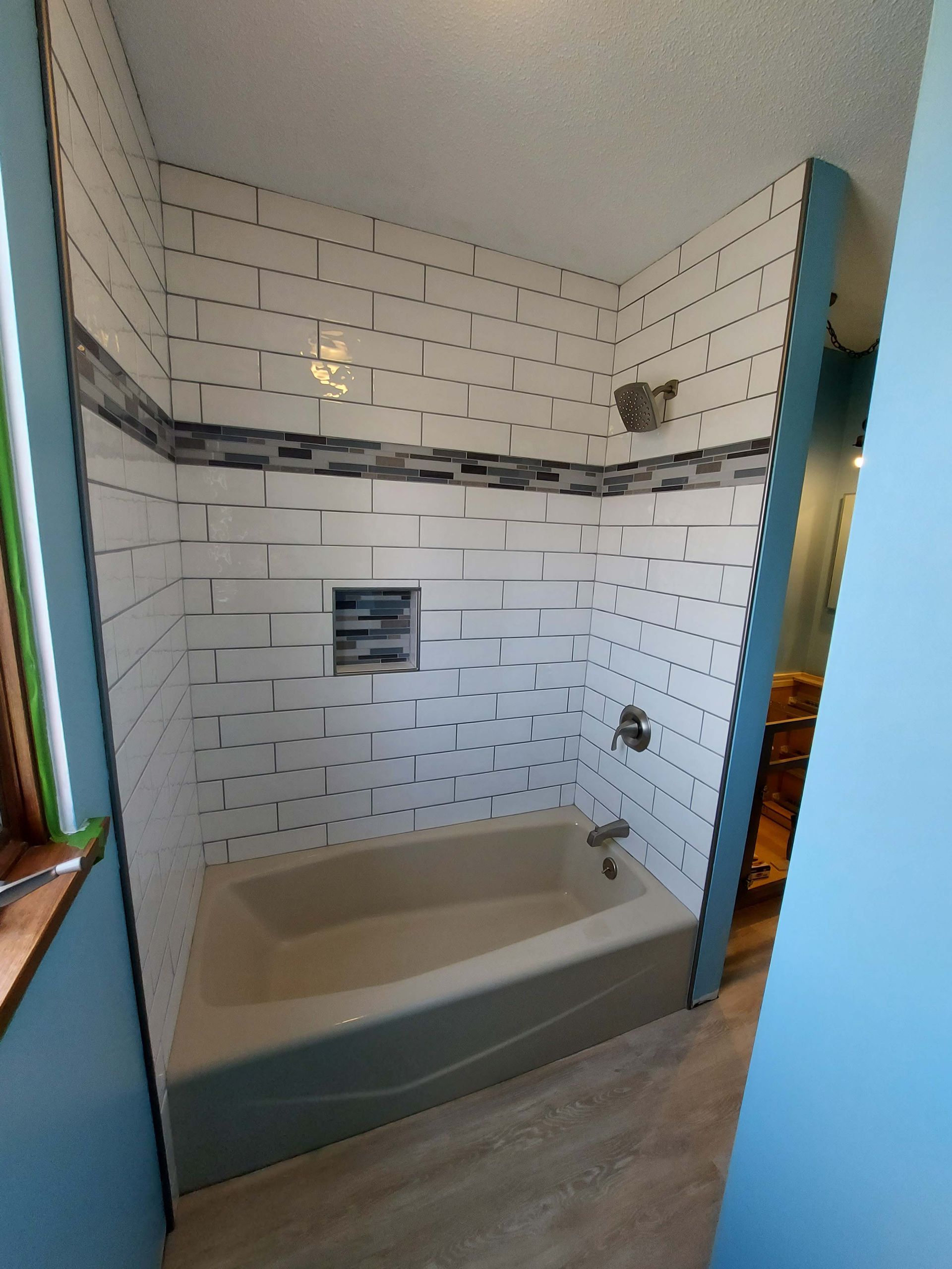 A bathroom with white tiles and a bathtub