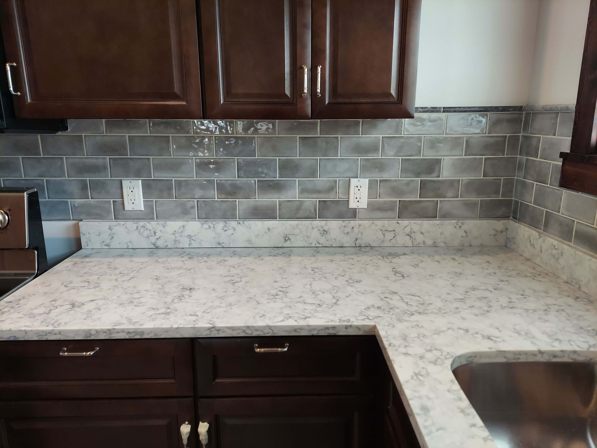 A kitchen with a white counter top and a stainless steel sink