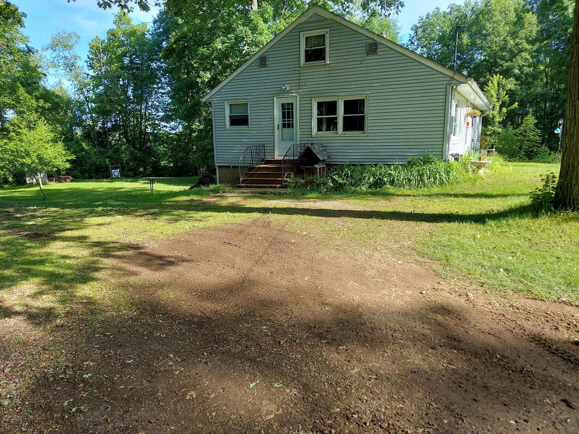 A small white house is sitting in the middle of a lush green field.