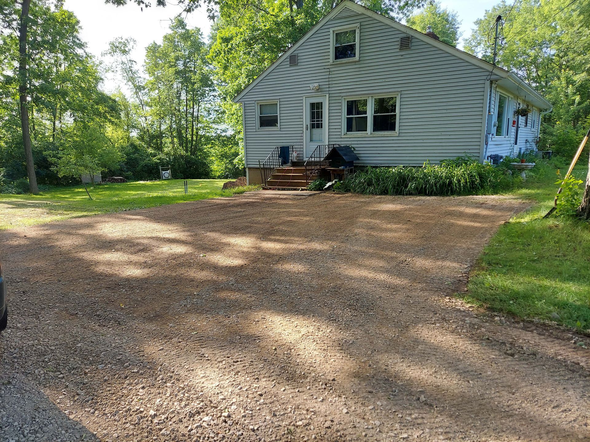 A white house with a gravel driveway in front of it.