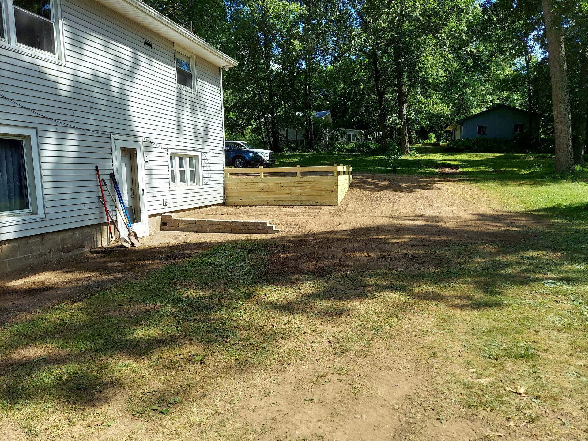 A white house with a wooden deck in front of it.