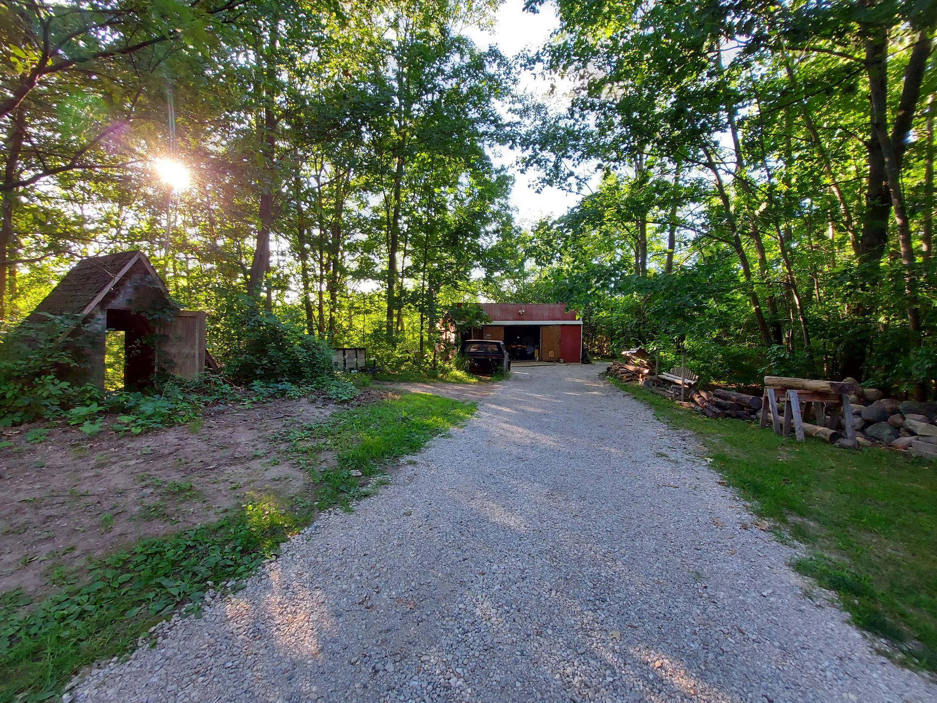 A gravel road leading to a garage in the woods.