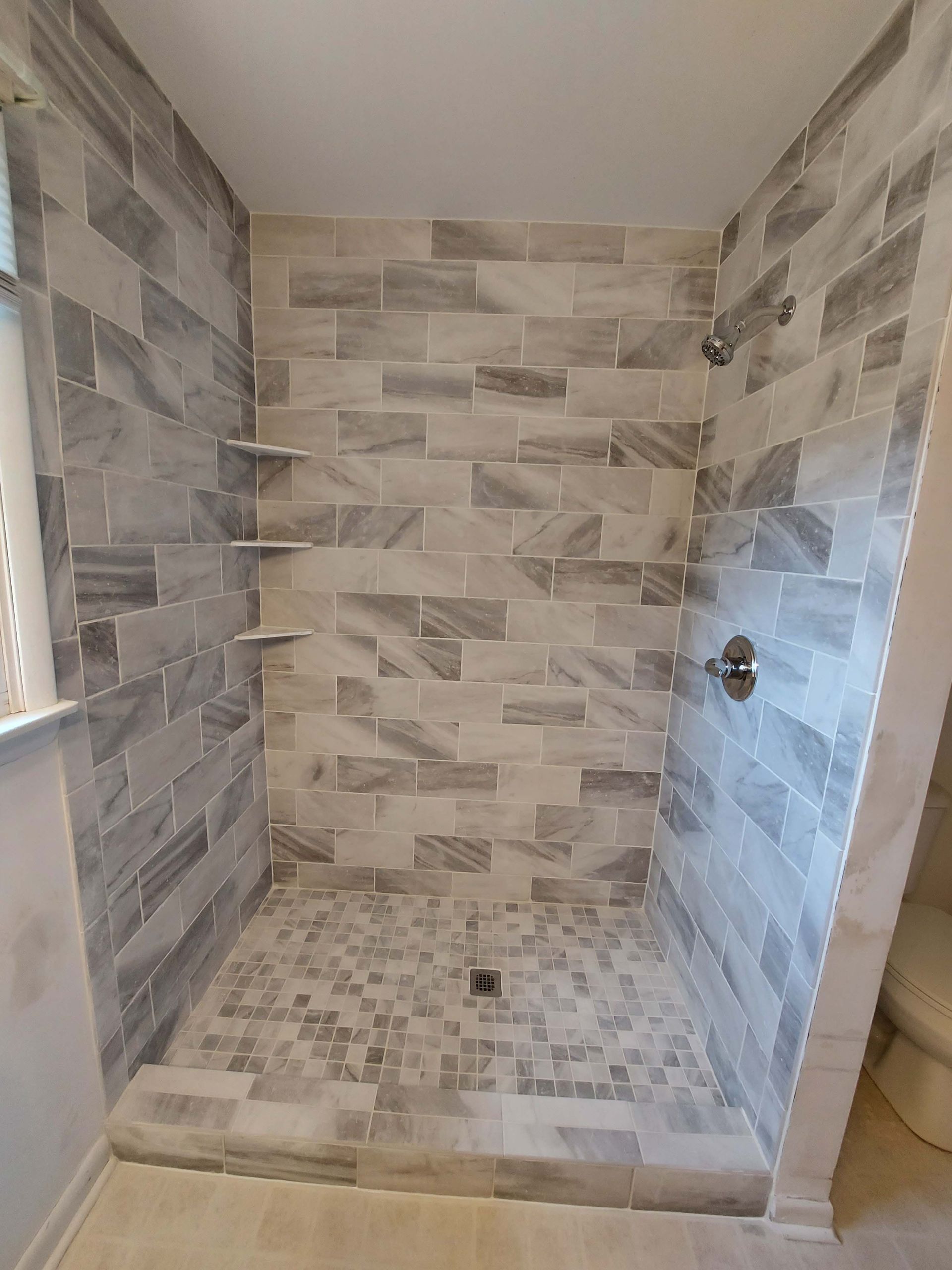 A bathroom with a walk in shower and a window.