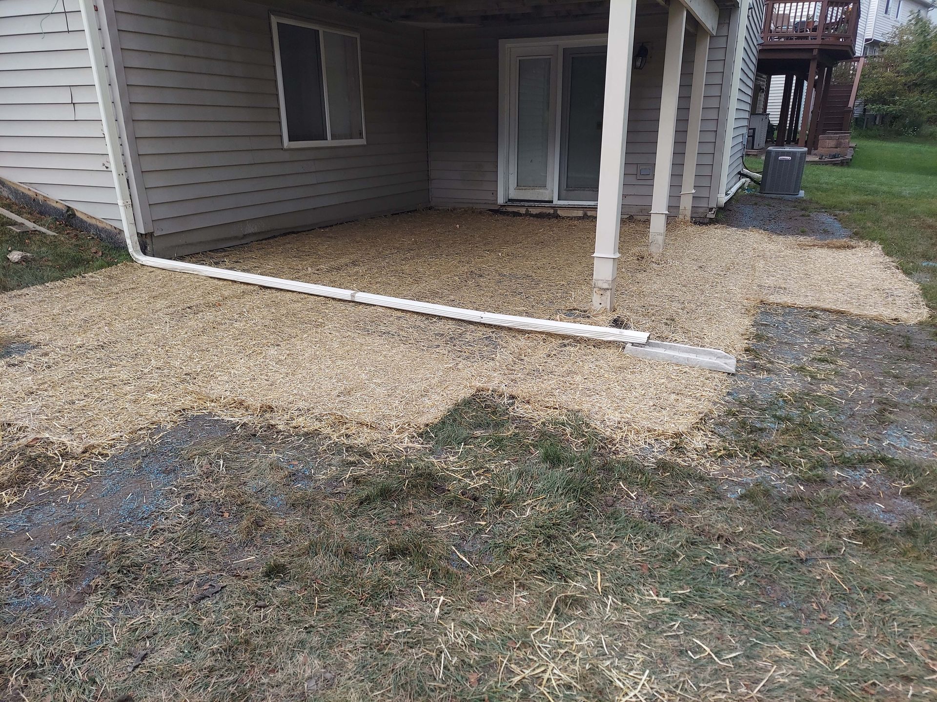 The backyard of a house with a patio and a drain pipe.