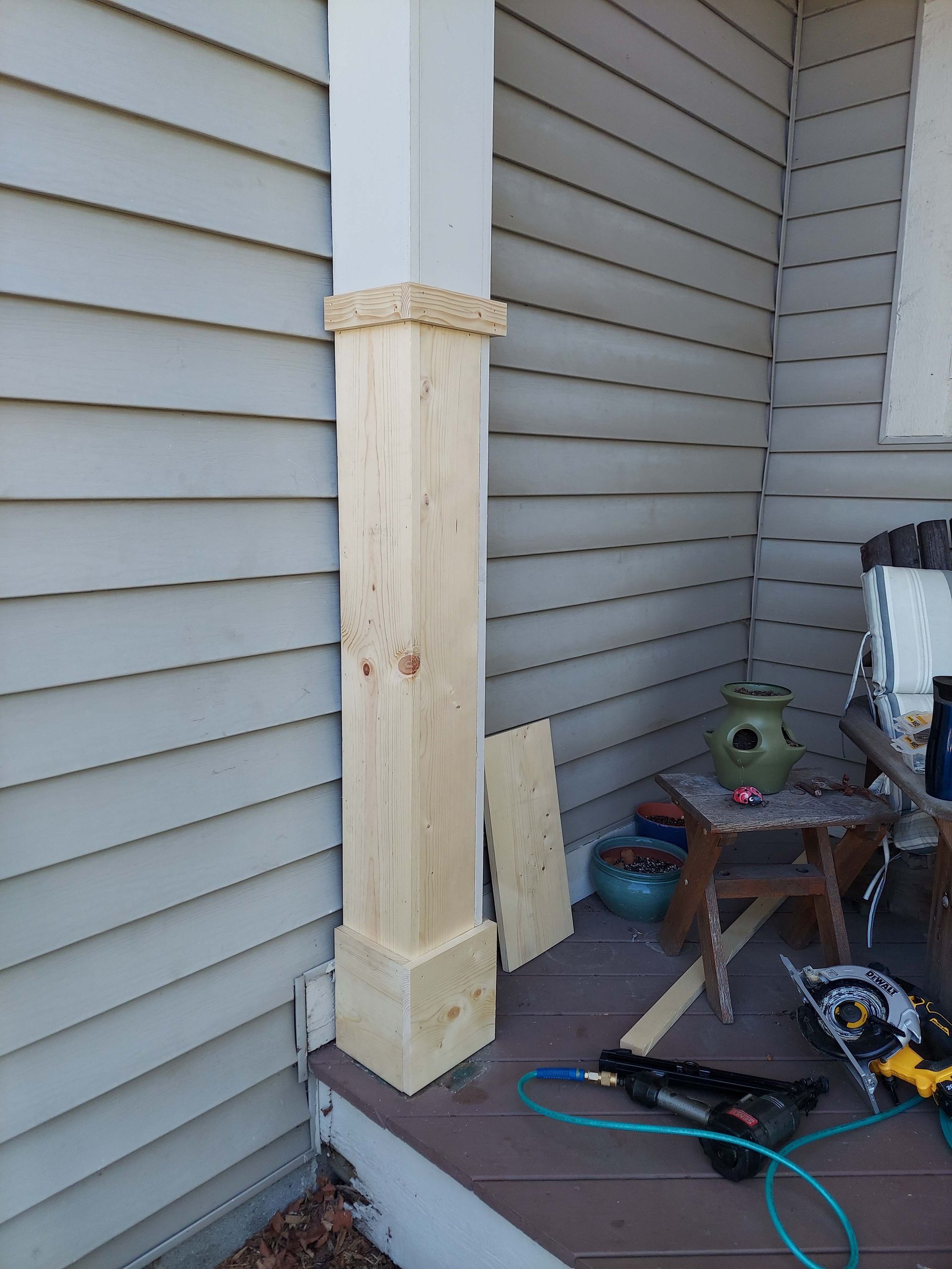 A wooden post is sitting on a porch next to a house.