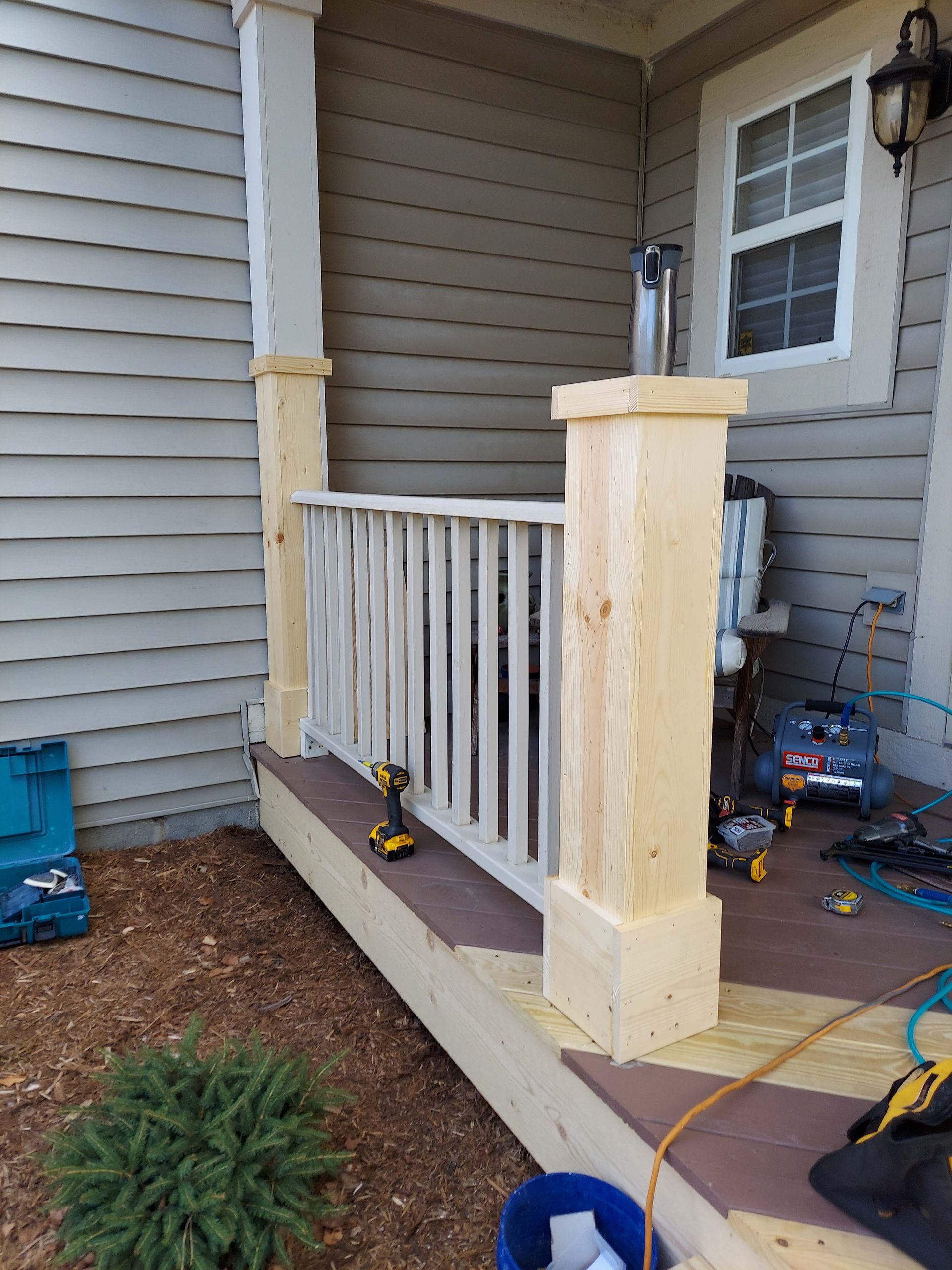 A wooden porch railing is being built on a house.
