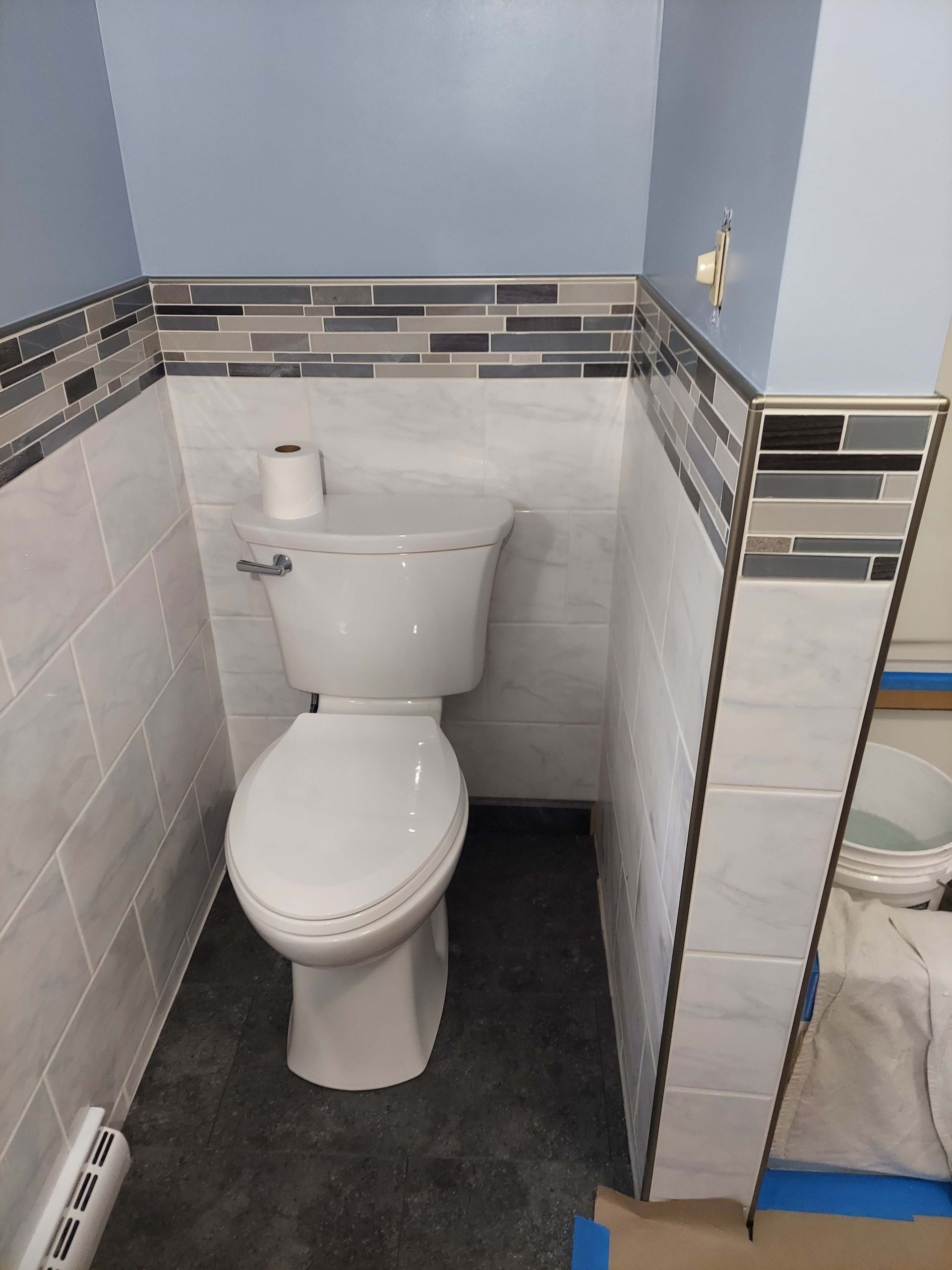 A toilet is sitting in a corner of a bathroom.