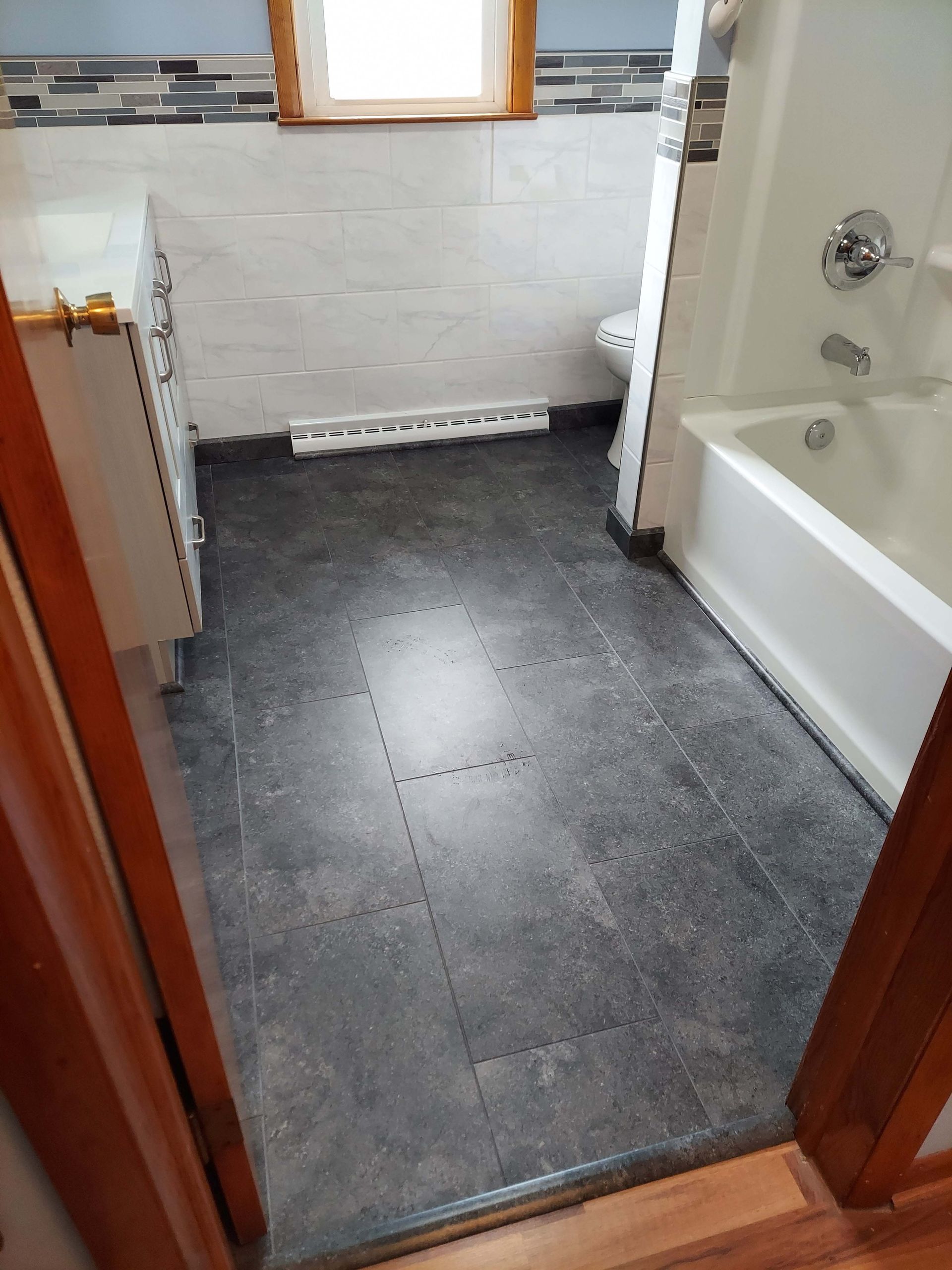 A bathroom with a bathtub , sink , toilet and window.