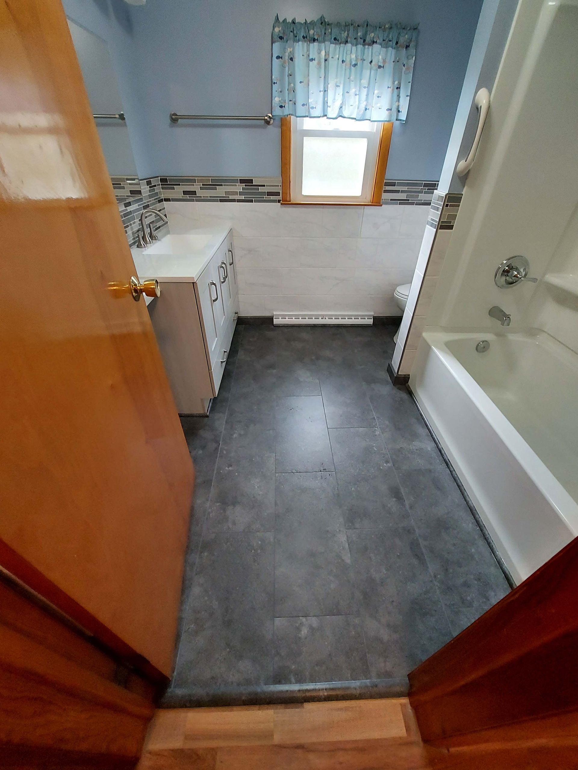 A bathroom with a tub , sink , toilet and window.