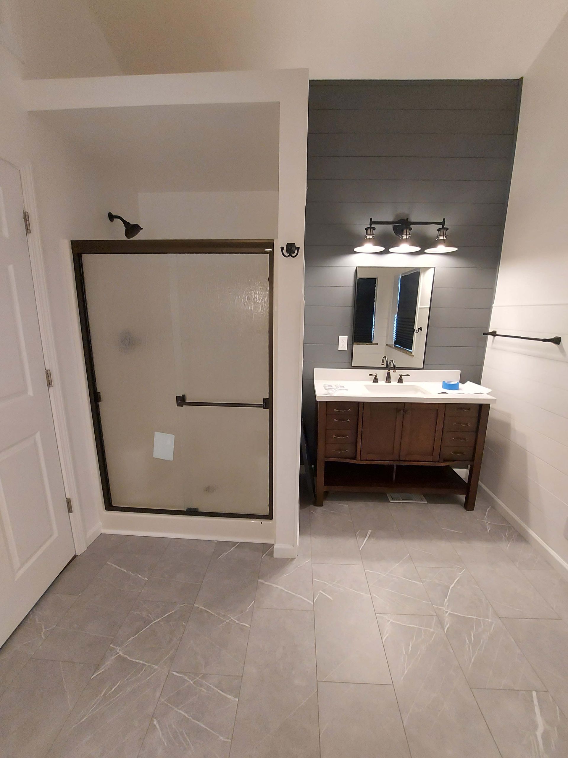 A bathroom with a walk in shower , sink and mirror.