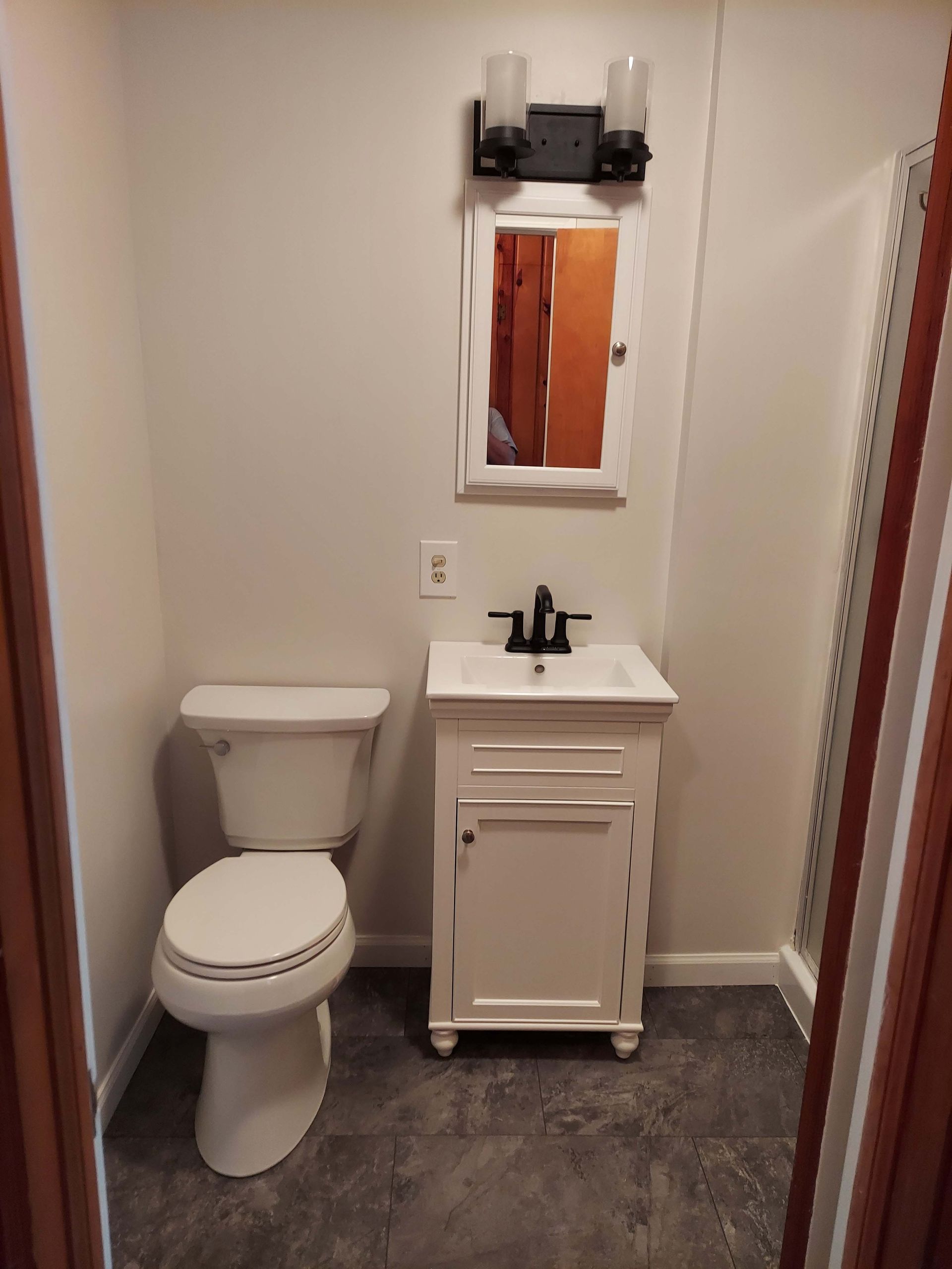 A bathroom with a toilet , sink and mirror.