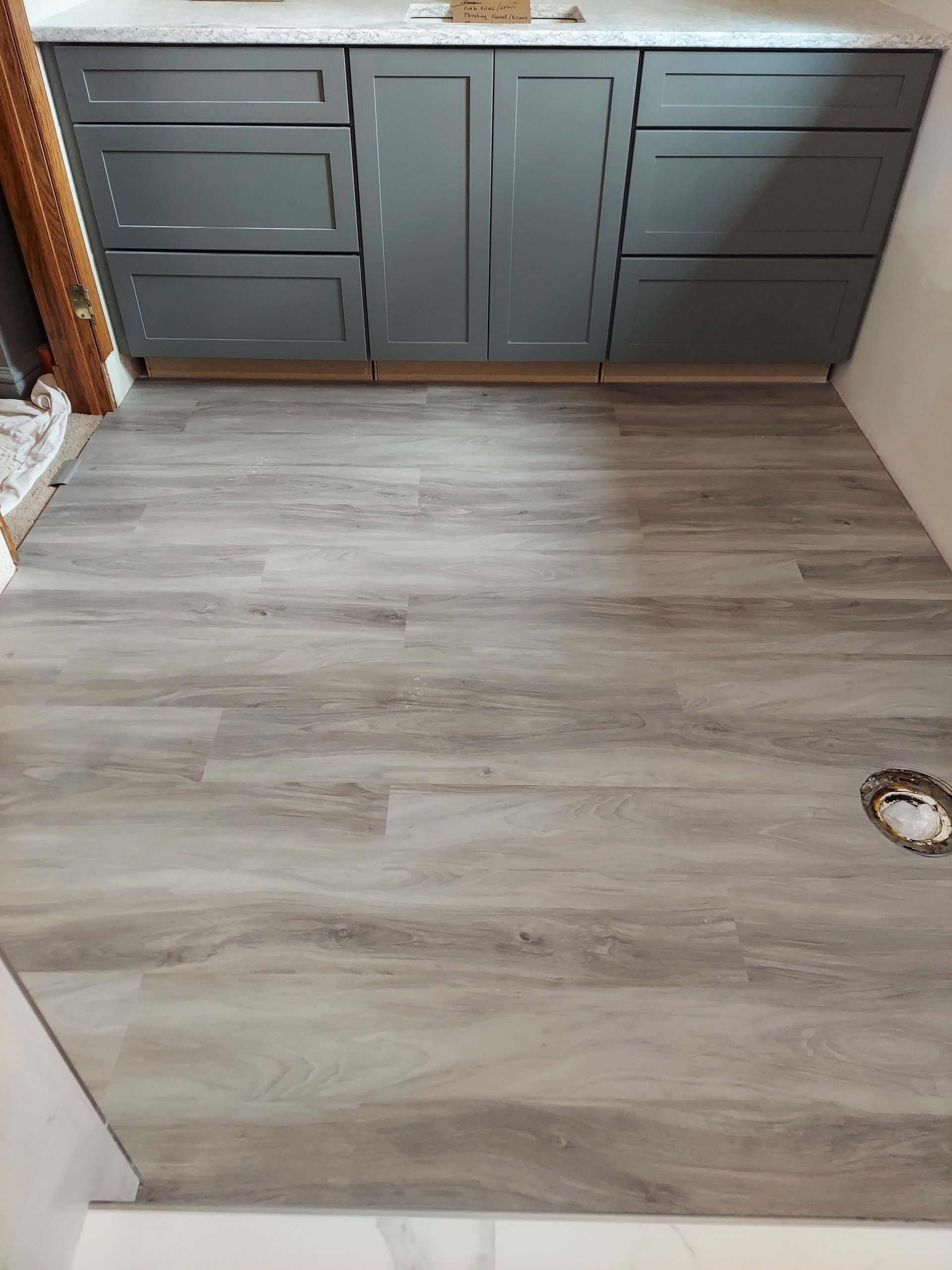 A bathroom with a wooden floor and gray cabinets.