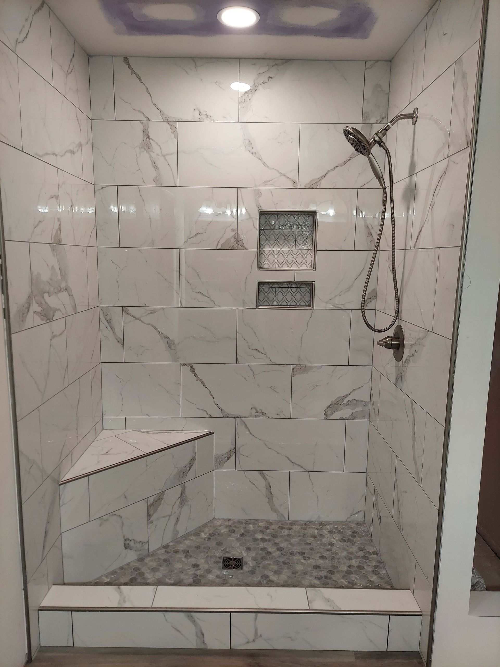 A shower with marble tiles and a shower head.
