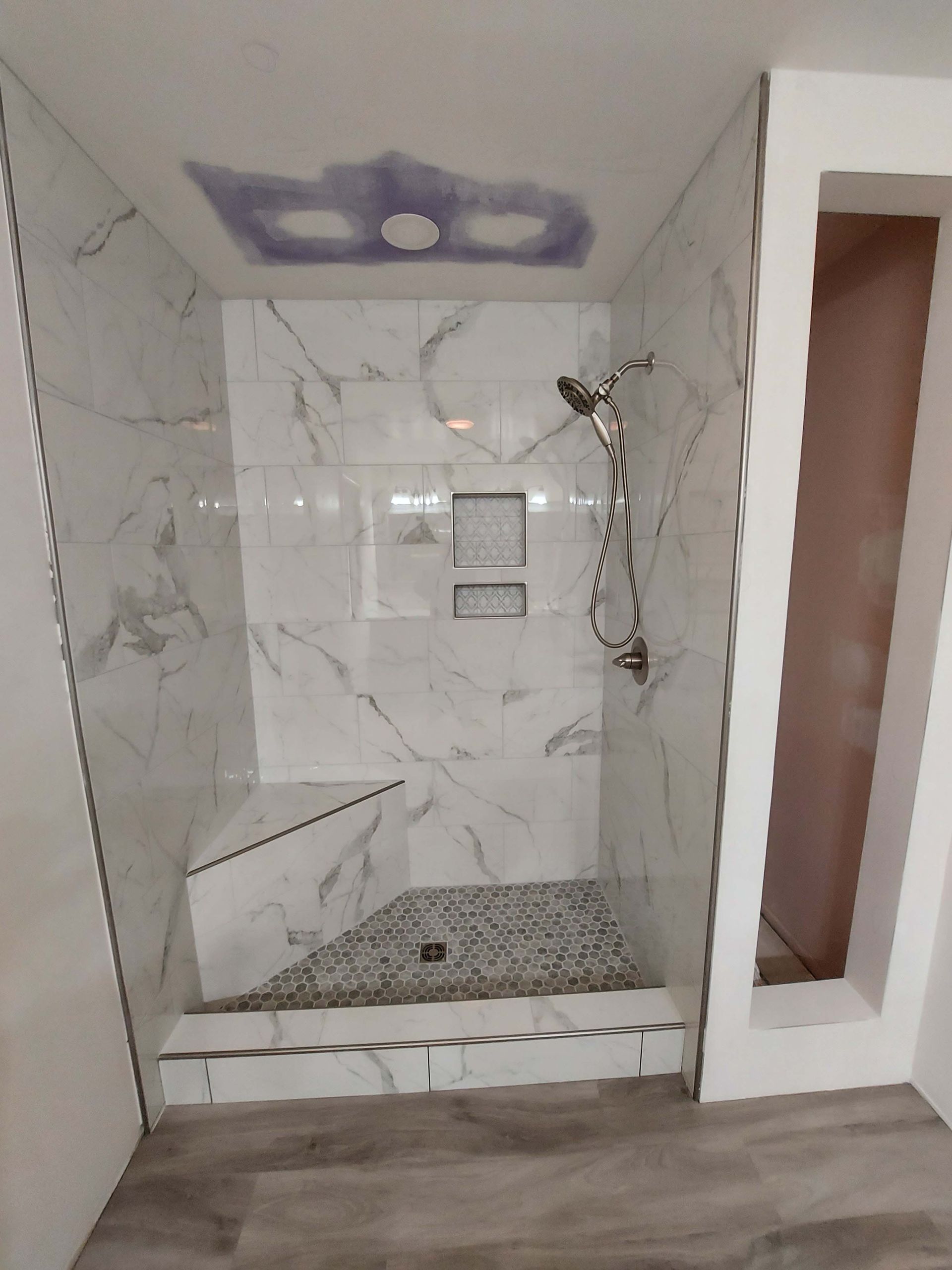 A bathroom with a walk in shower and a shower head.