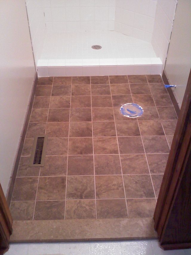A bathroom with a tiled floor and a walk in shower.