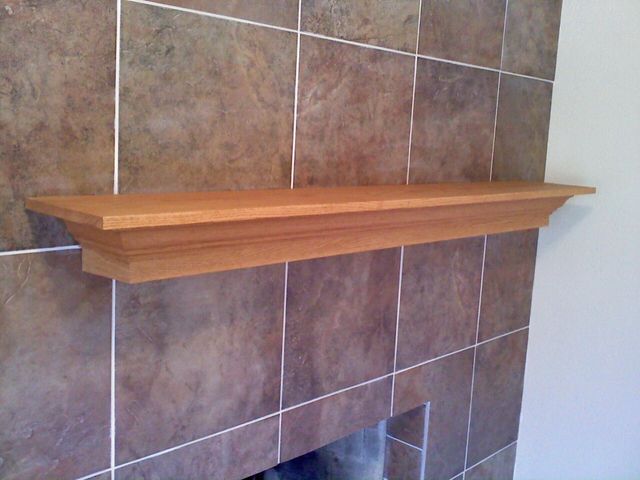 A fireplace with a wooden shelf on top of it