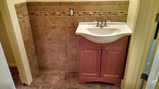 A bathroom with a pink vanity and a sink.