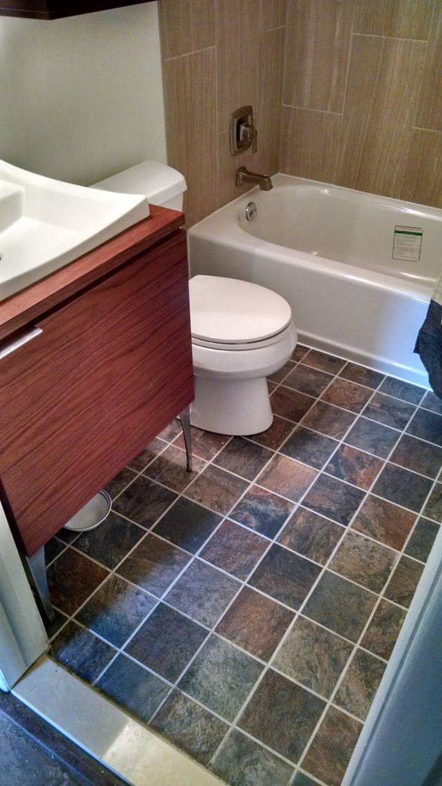 A bathroom with a toilet , sink , bathtub and tile floor.