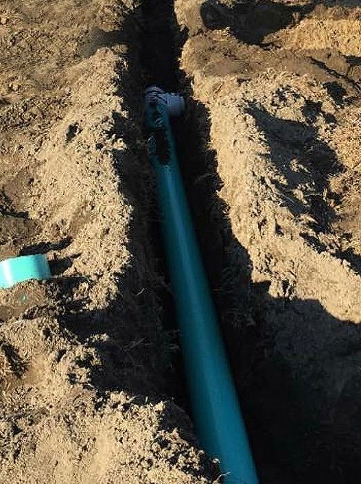 A blue pipe is sticking out of a hole in the ground.
