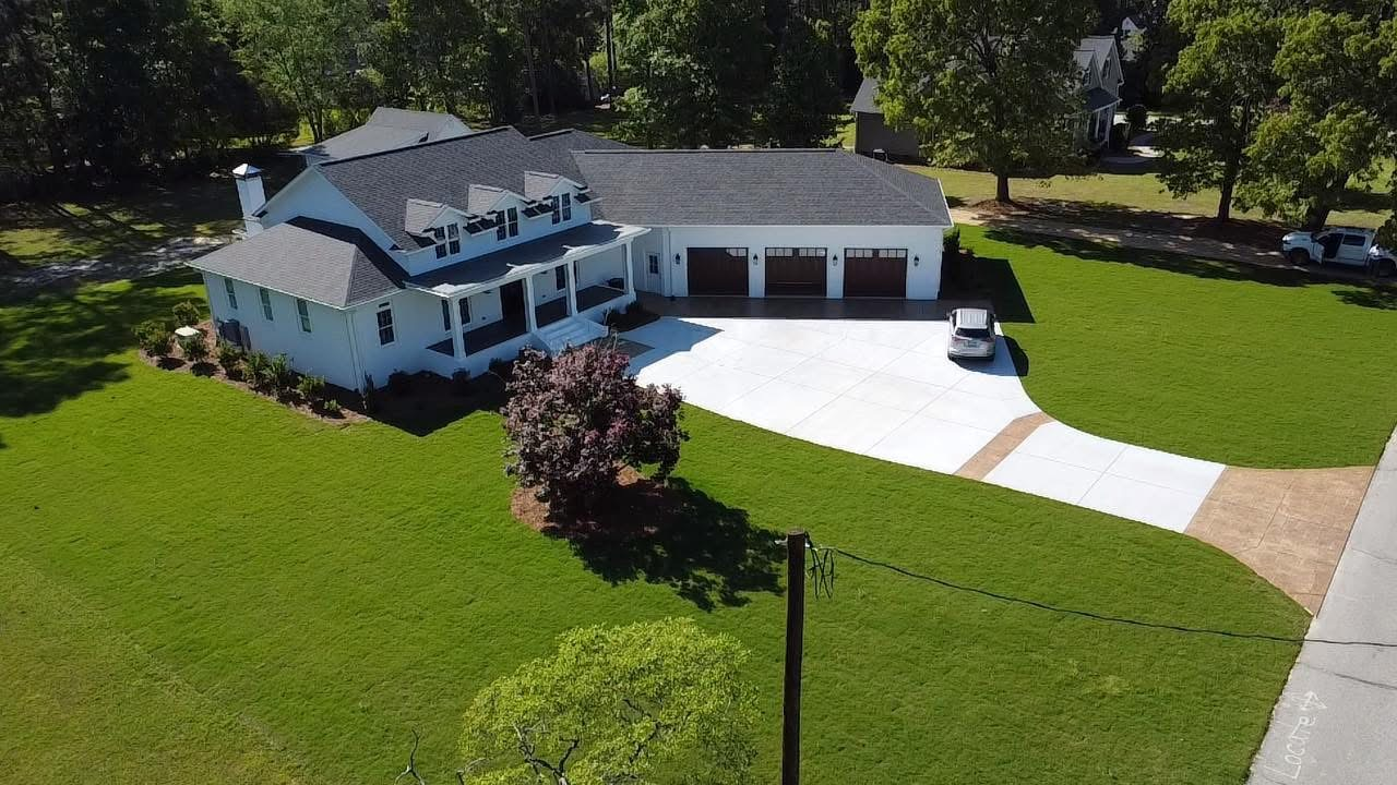 An aerial view of a house with a gray roof and wide lawn.