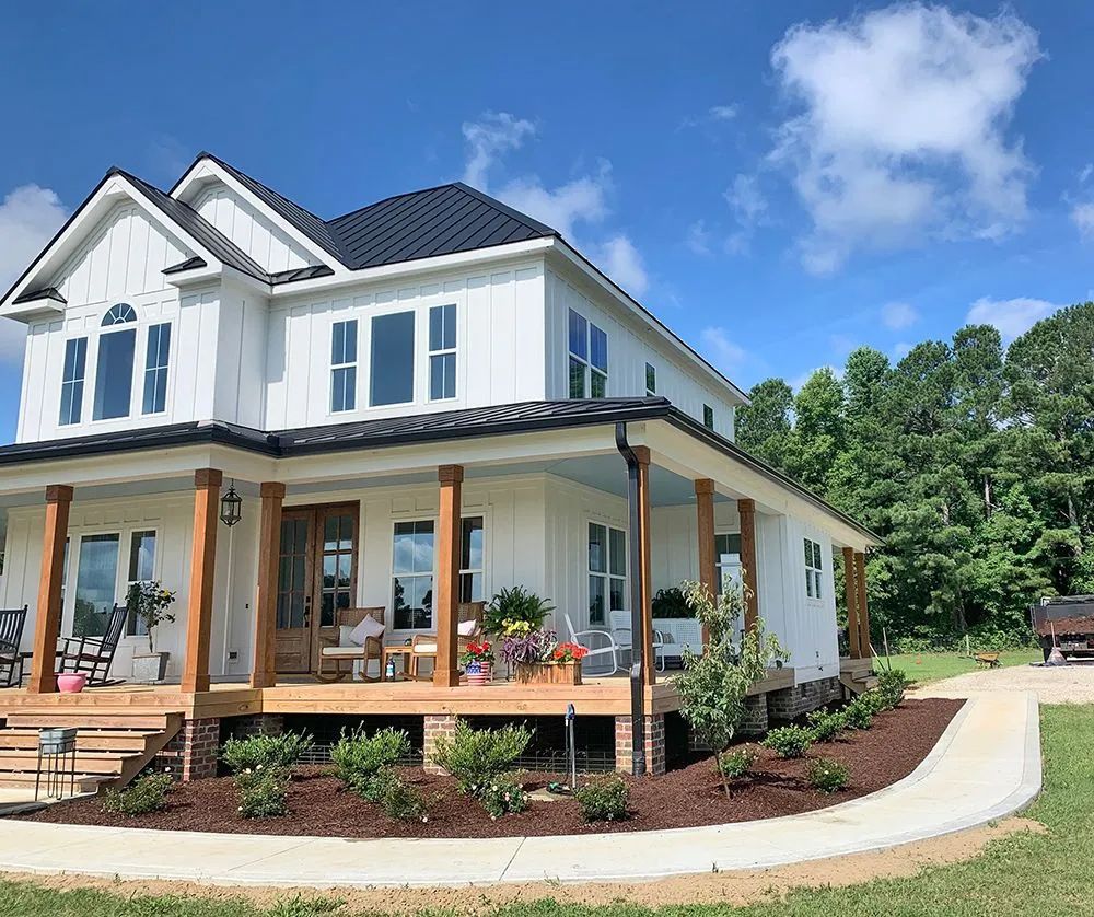 A large white house with a black roof and a large porch.