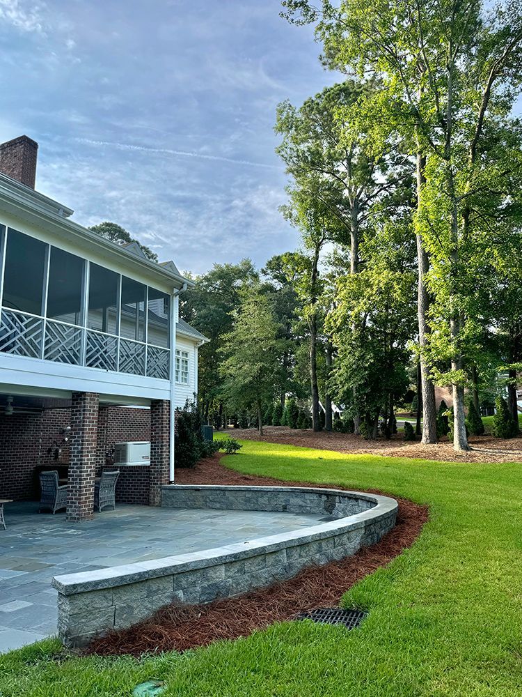 A large house with a screened in porch and a large lawn in front of it.