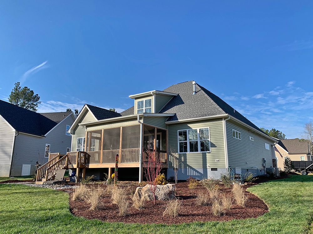 The back of a house with a screened in porch and a deck.