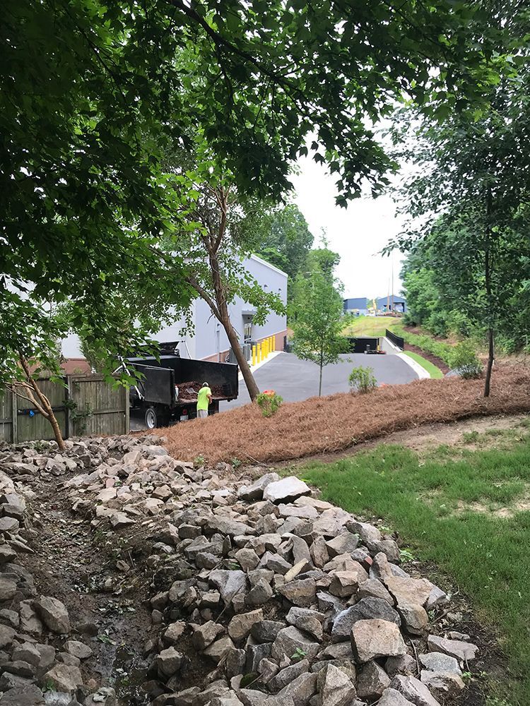 A dump truck is parked on a hill next to a pile of rocks.