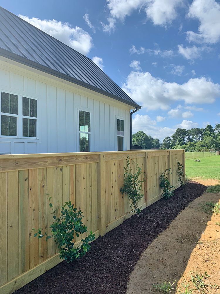 A wooden fence is in front of a white house.
