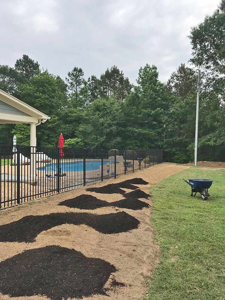 A wheelbarrow is sitting in the grass next to a pool.