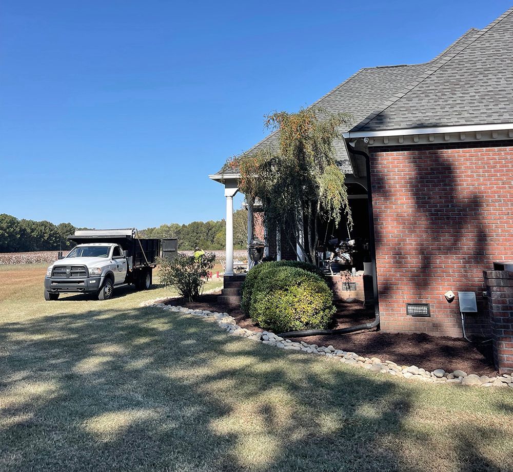 A dump truck is parked in front of a brick house.