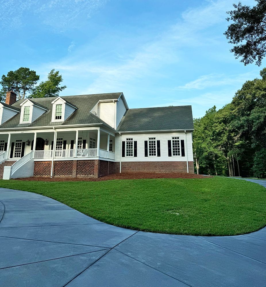 A large white house with a green roof and a large porch