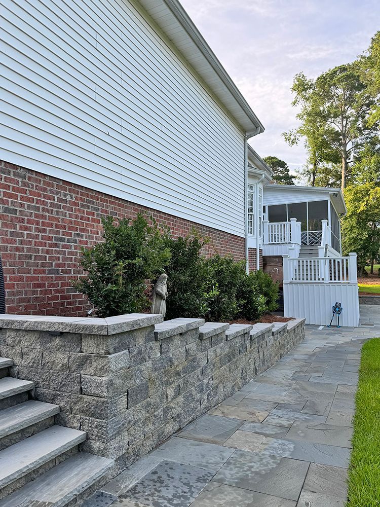 A stone walkway leading to a house with a screened in porch.